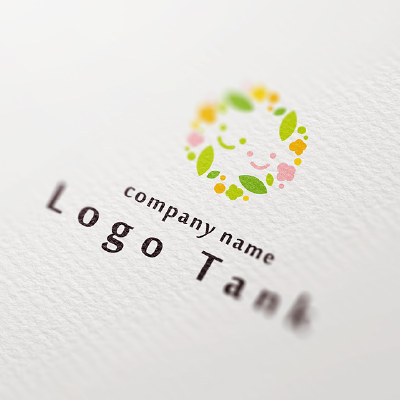 花輪の中に子供の笑顔が浮かぶロゴ